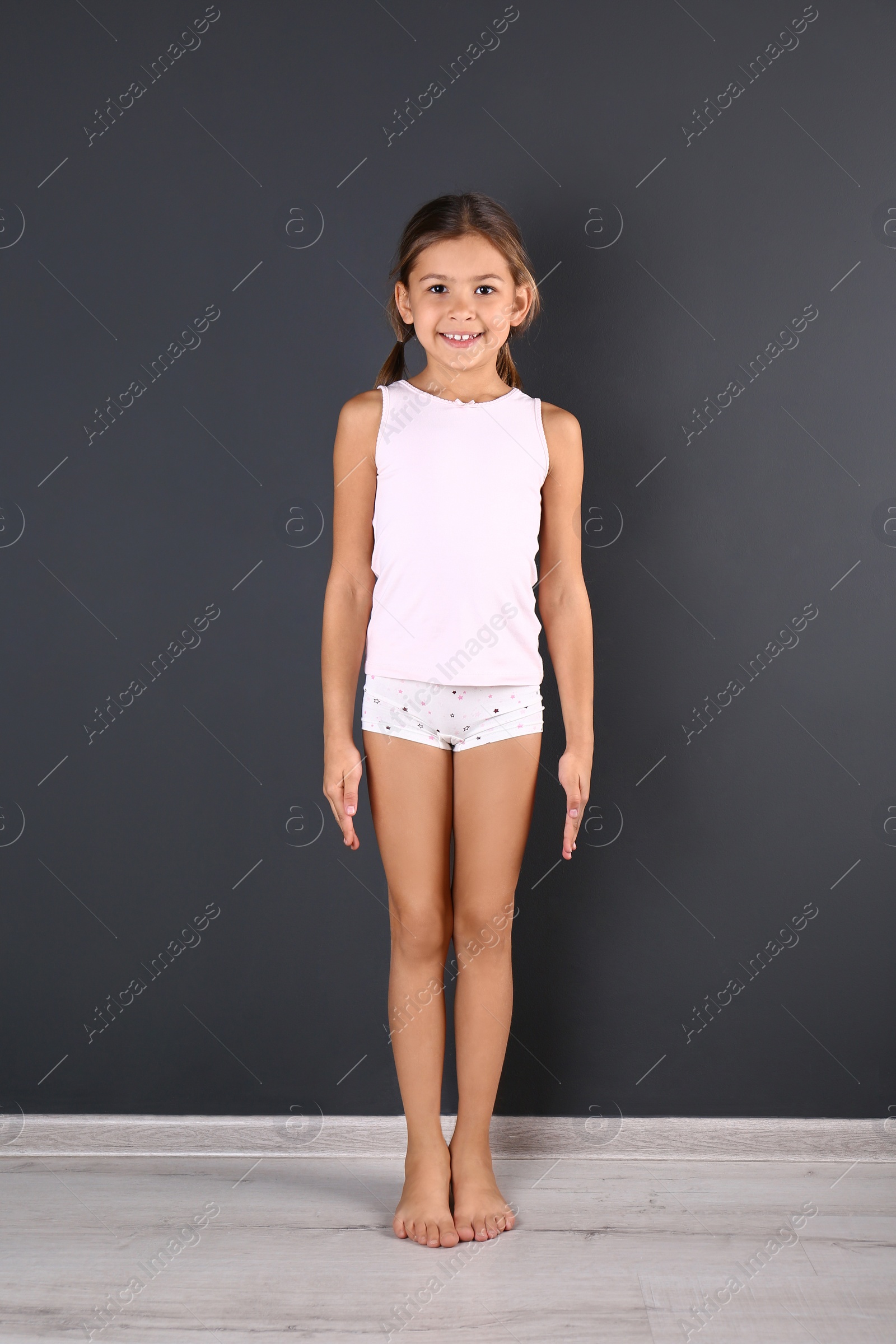 Photo of Cute little girl in underwear near dark wall