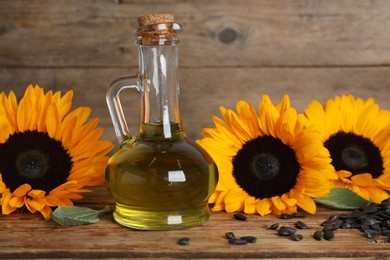 Photo of Sunflower cooking oil, seeds and yellow flowers on wooden table