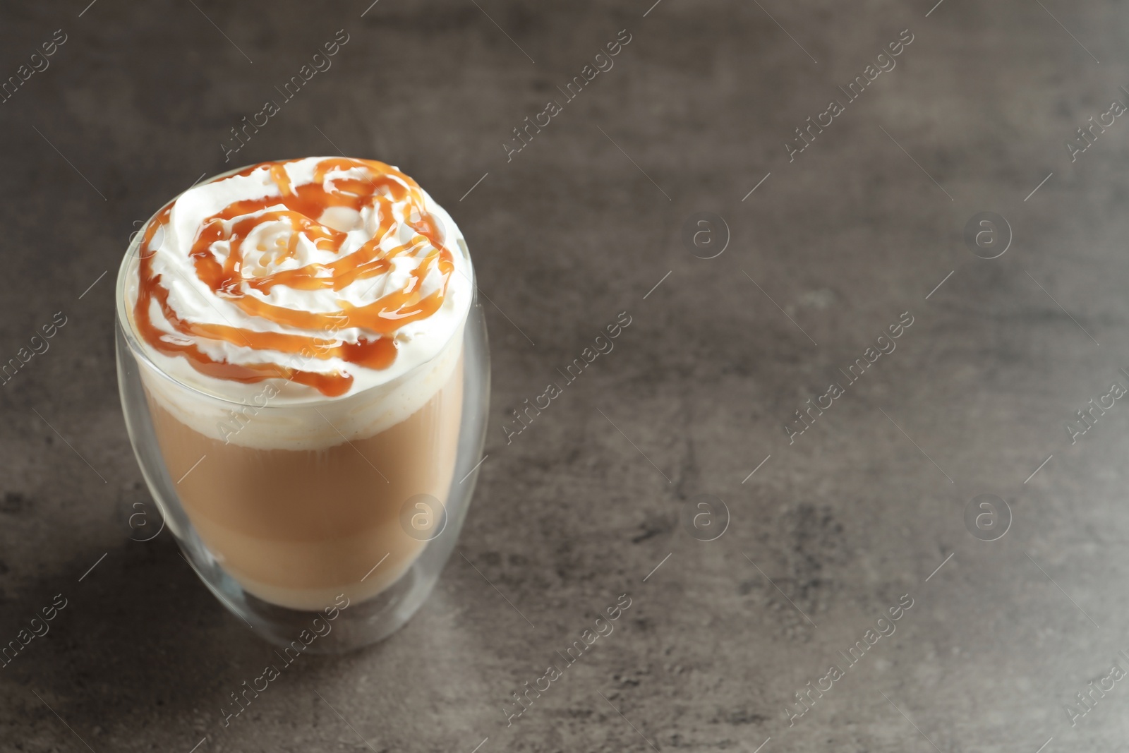 Photo of Glass with delicious caramel frappe on grey background