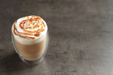 Photo of Glass with delicious caramel frappe on grey background