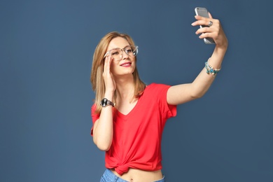 Attractive young woman taking selfie on color background