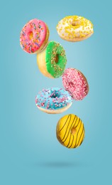 Sweet tasty donuts falling on light blue background