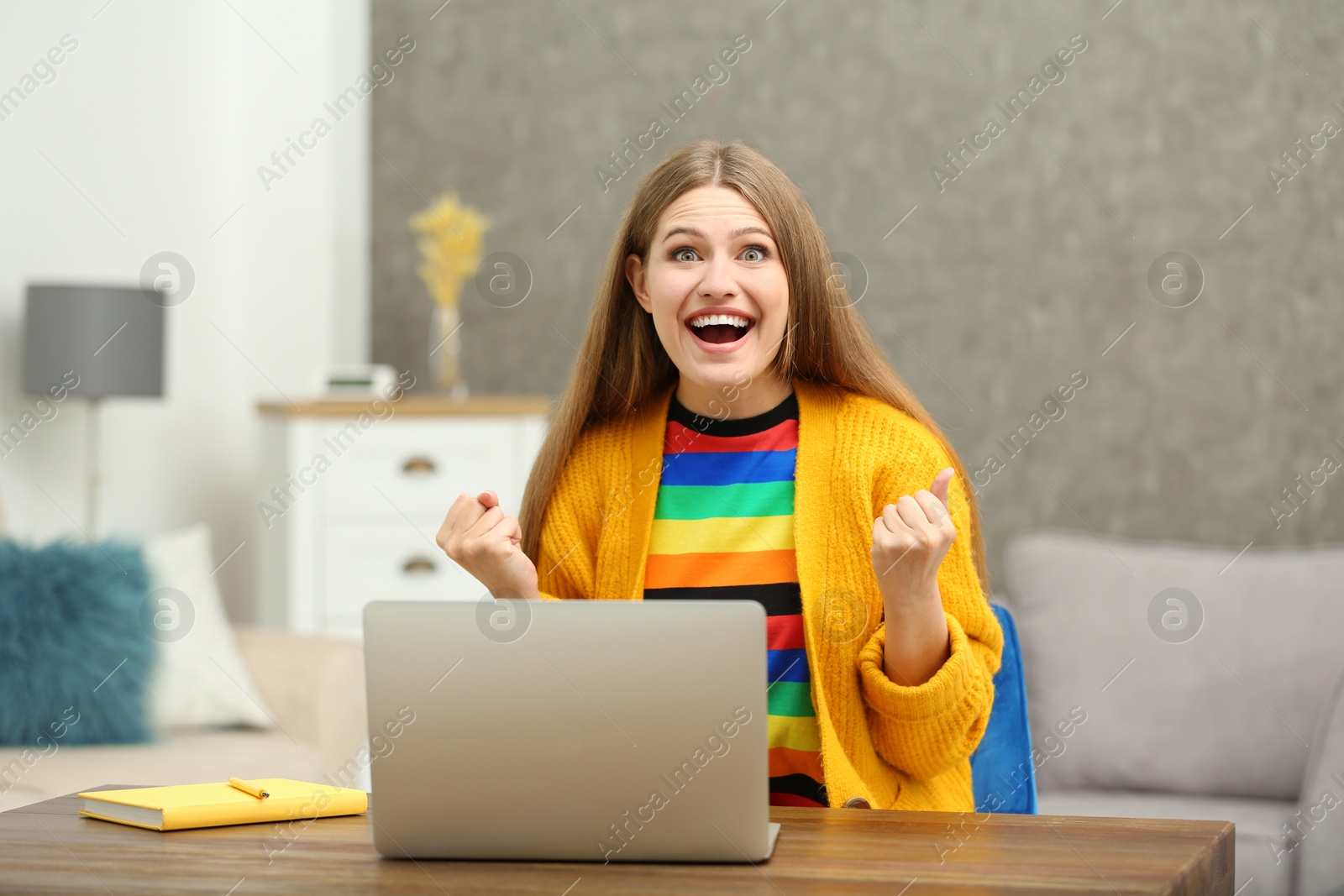 Photo of Happy young woman playing online lottery using laptop at home