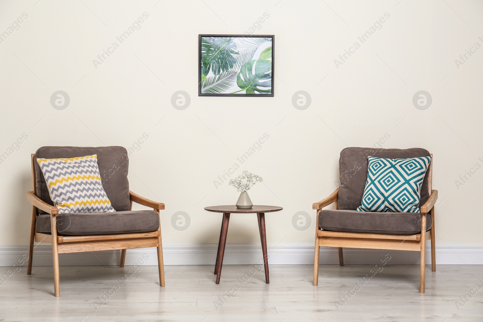 Photo of Room interior with modern armchairs and table near light wall