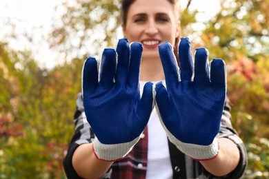 Photo of Woman showing protective gloves in garden, focus on hands