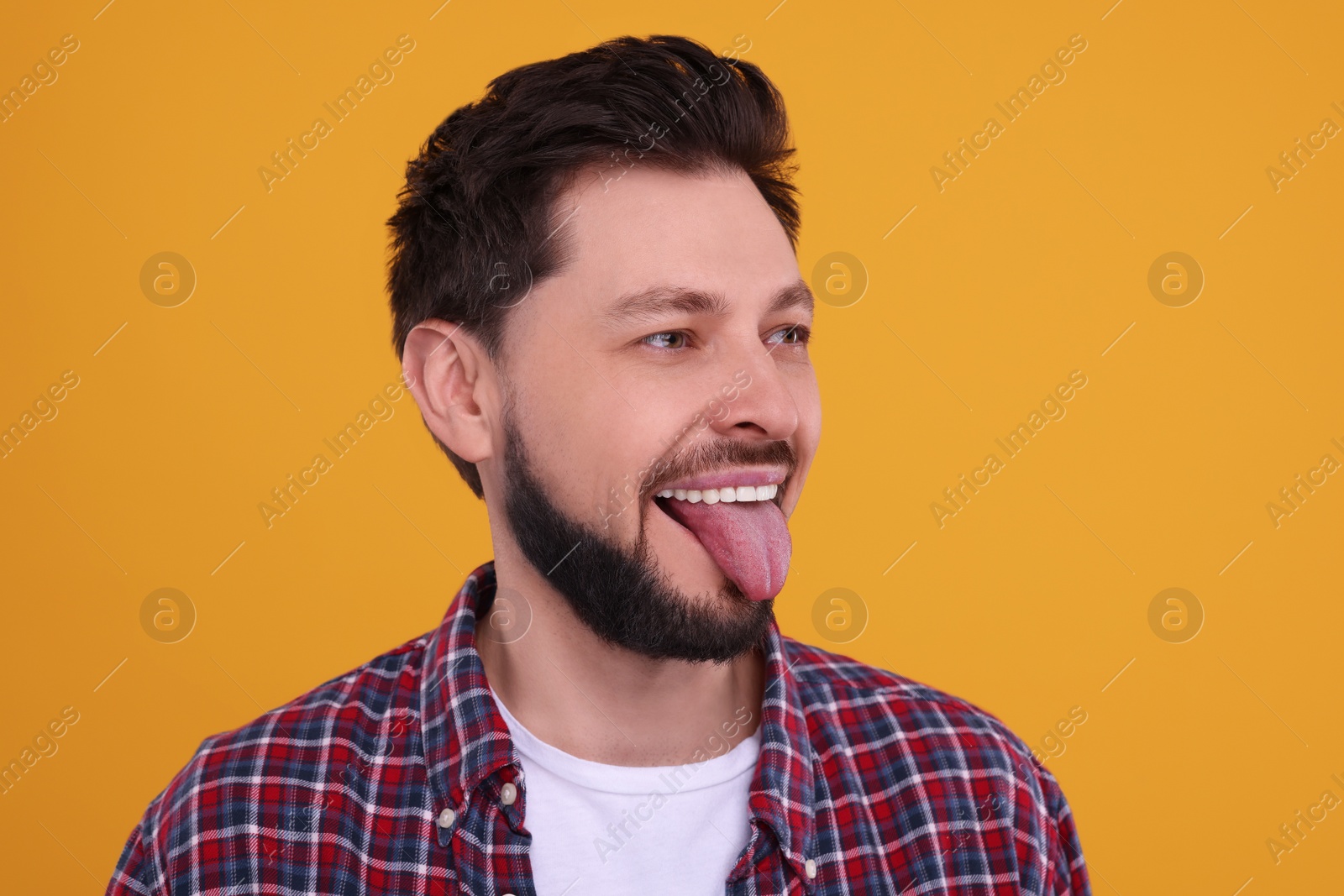 Photo of Happy man showing his tongue on orange background