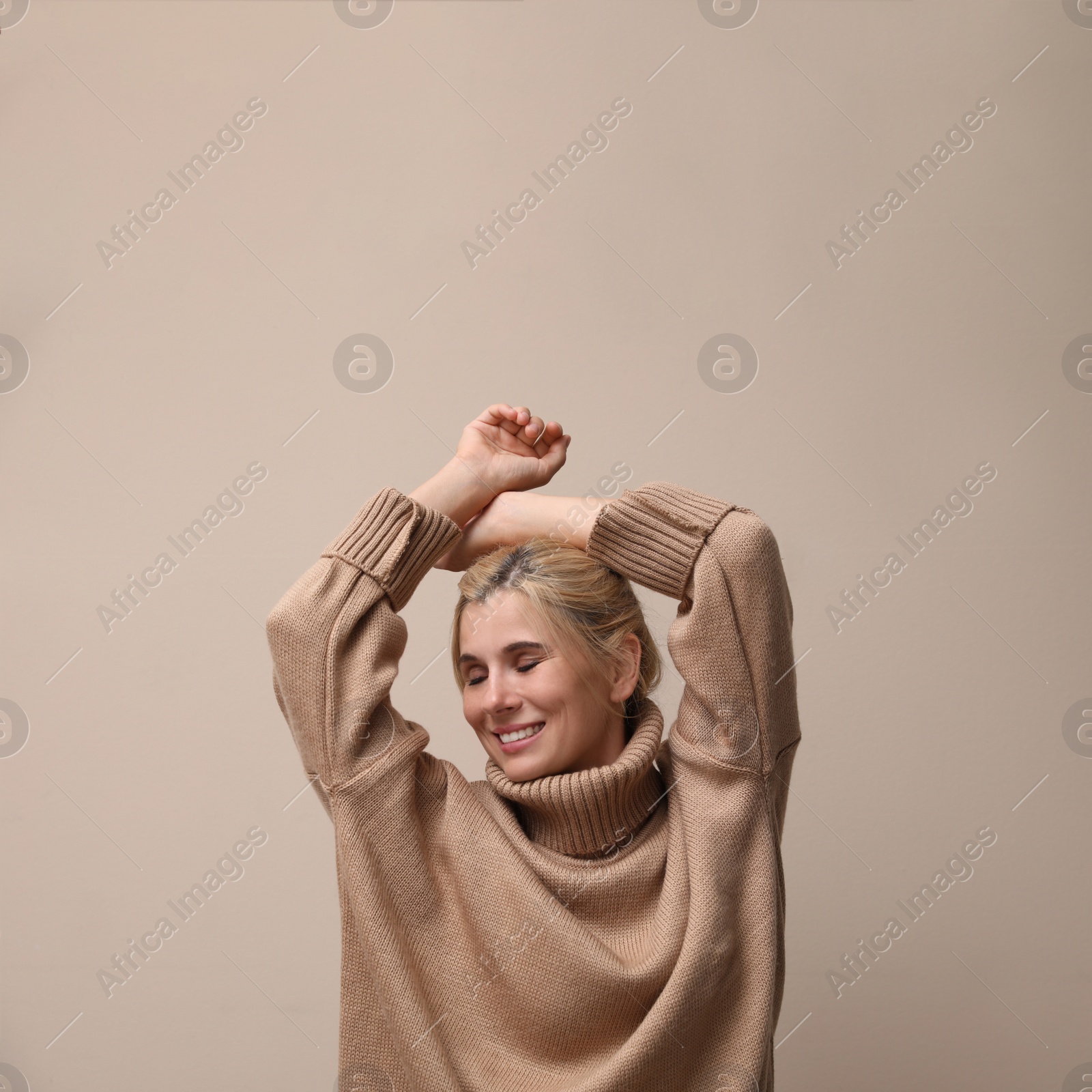Photo of Happy woman in stylish sweater on beige background