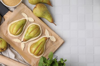 Photo of Board with raw dough, fresh pears and mint on white tiled table, flat lay. Space for text