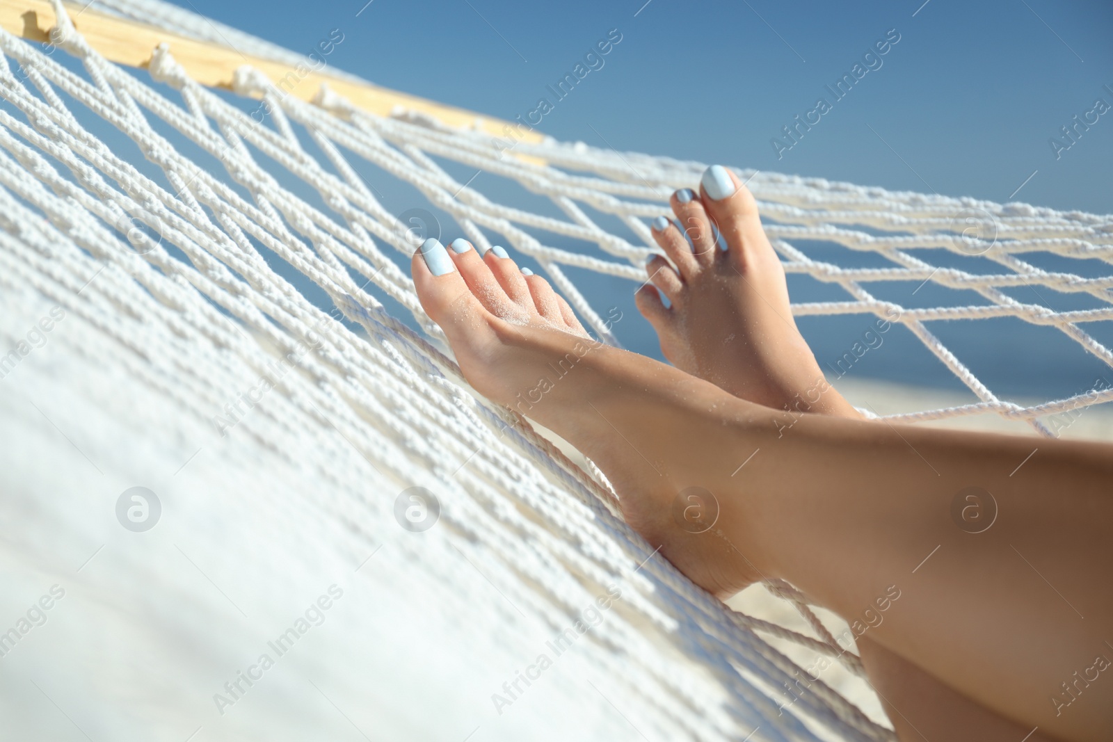Photo of Young woman relaxing in hammock on beach, closeup