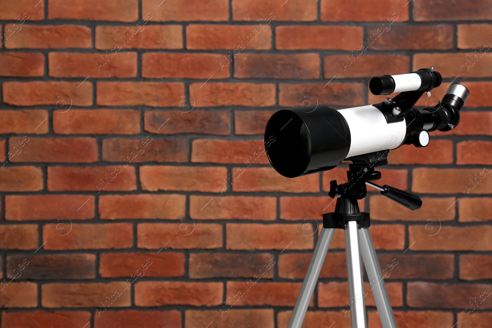 Photo of Tripod with modern telescope near brick wall. Space for text