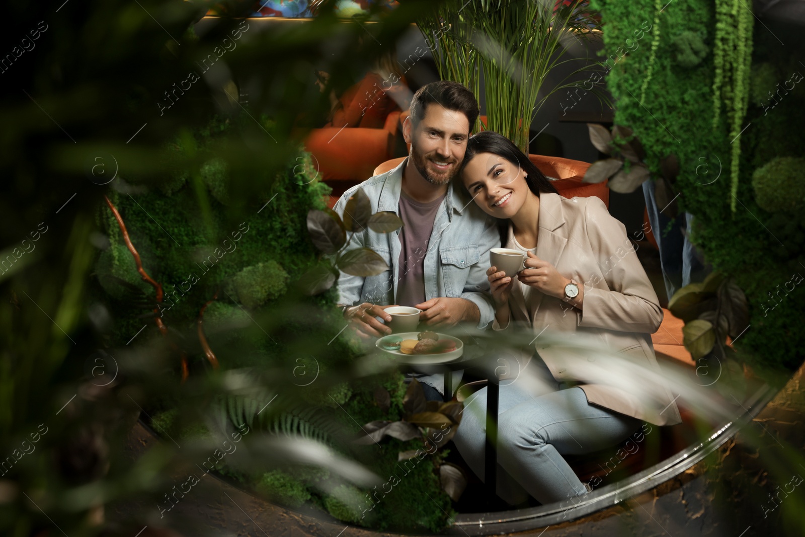 Photo of Couple with coffee and macarons spending time together in cafe