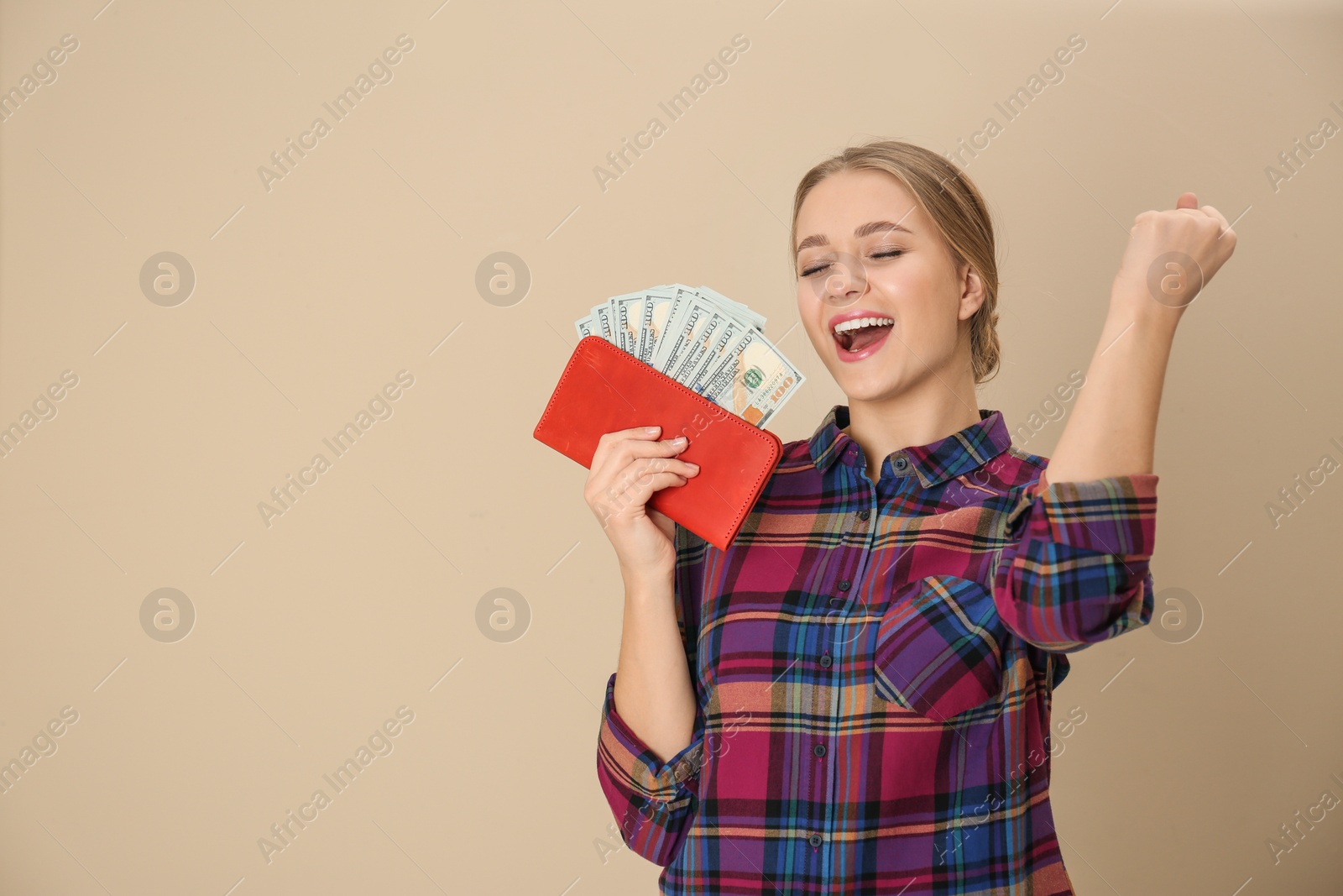 Photo of Happy young woman with wallet full of money on color background. Space for text