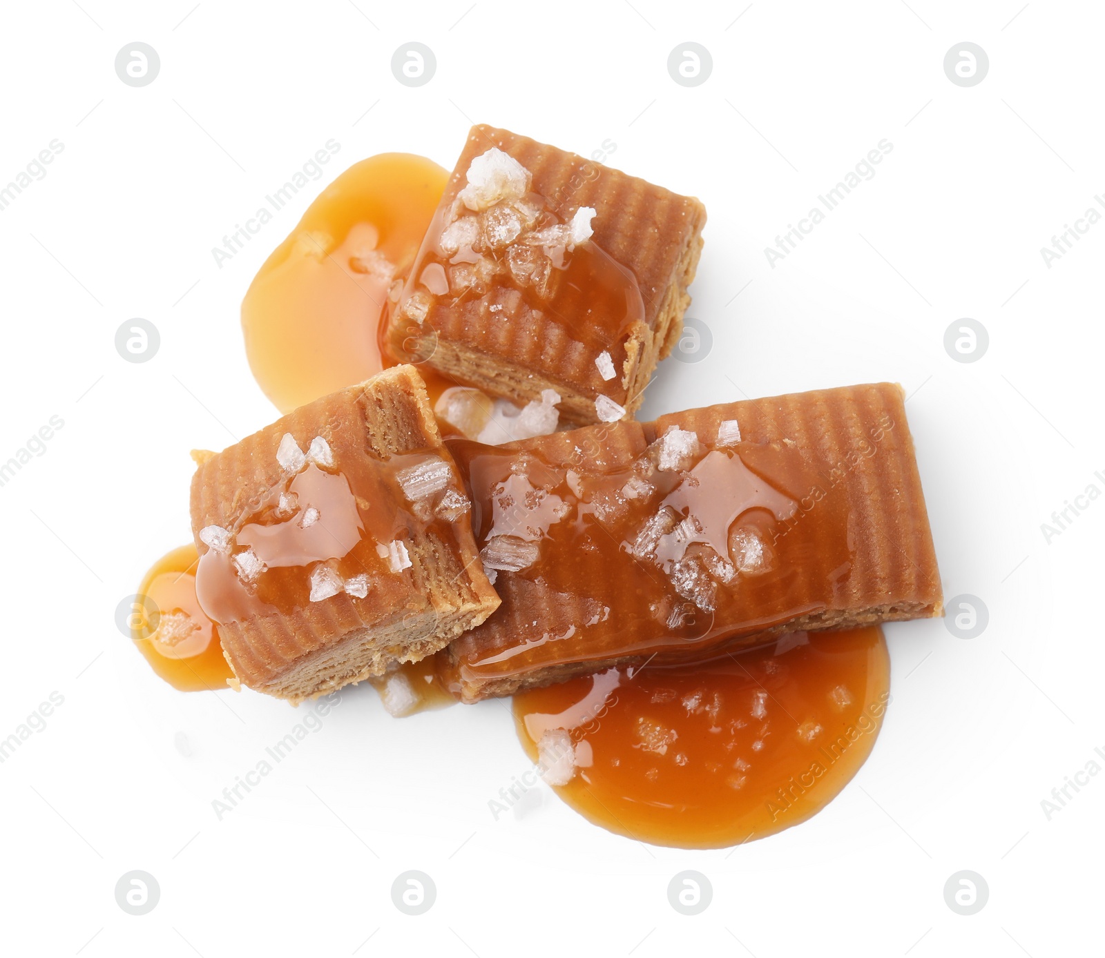 Photo of Yummy caramel candies and sea salt isolated on white, top view