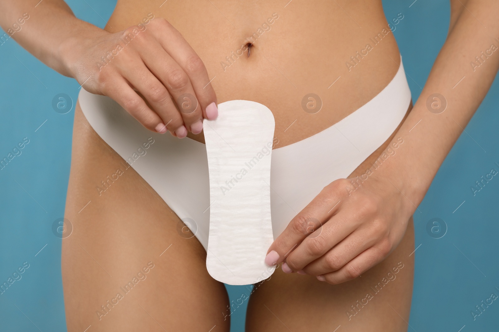 Photo of Woman in white panties with menstrual pad on light blue background, closeup