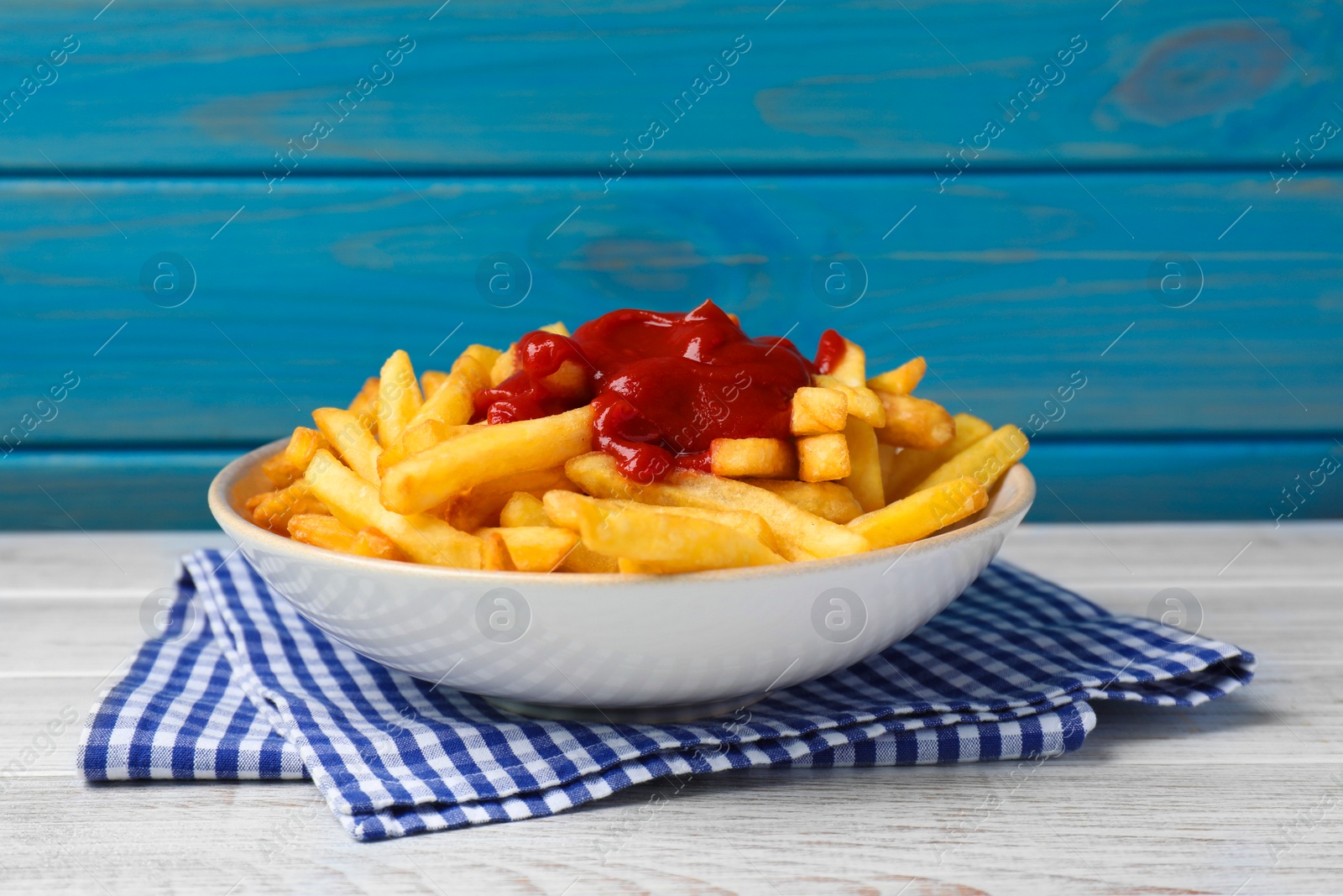 Photo of Bowl of tasty french fries on white wooden table
