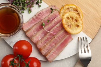 Pieces of delicious tuna steak served on light grey table, flat lay