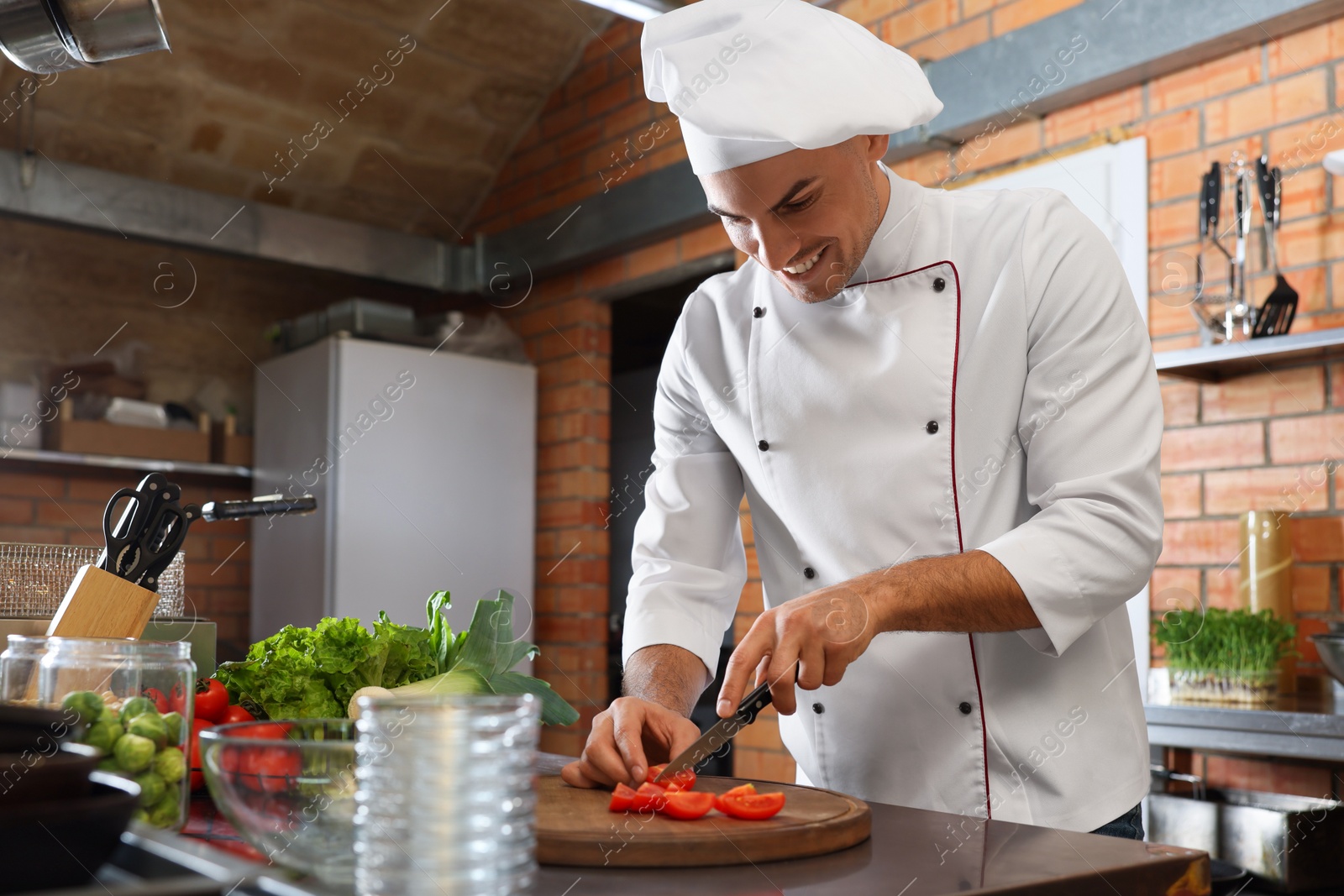 Photo of Professional chef cutting fresh tomatoes in restaurant kitchen