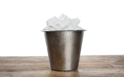 Metal bucket with ice cubes on wooden table against white background