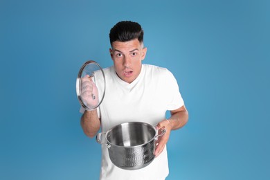 Surprised man with pot on light blue background