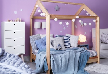 Photo of Child's room interior with comfortable bed and garland