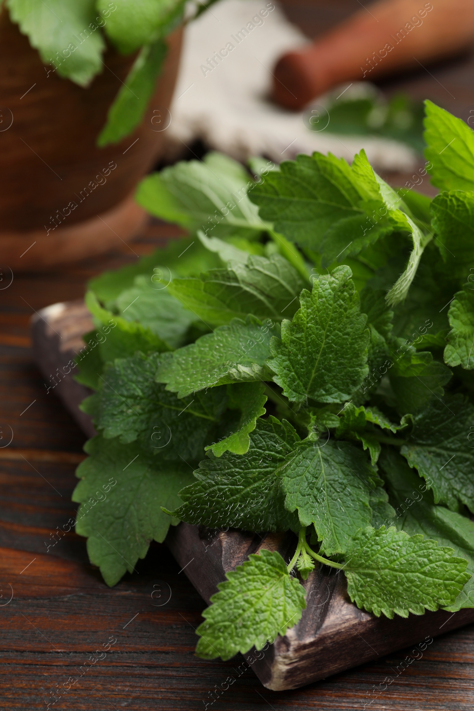 Photo of Fresh green lemon balm leaves on wooden table, closeup