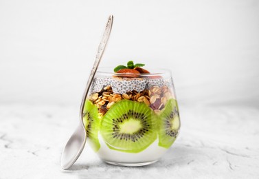 Photo of Delicious dessert with kiwi, chia seeds and spoon on light textured table