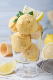 Yummy lemon ice cream served on white wooden table, closeup