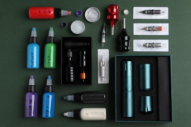 Photo of Flat lay composition with tattoo equipment on dark green background