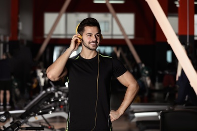 Photo of Young man listening to music with headphones at gym