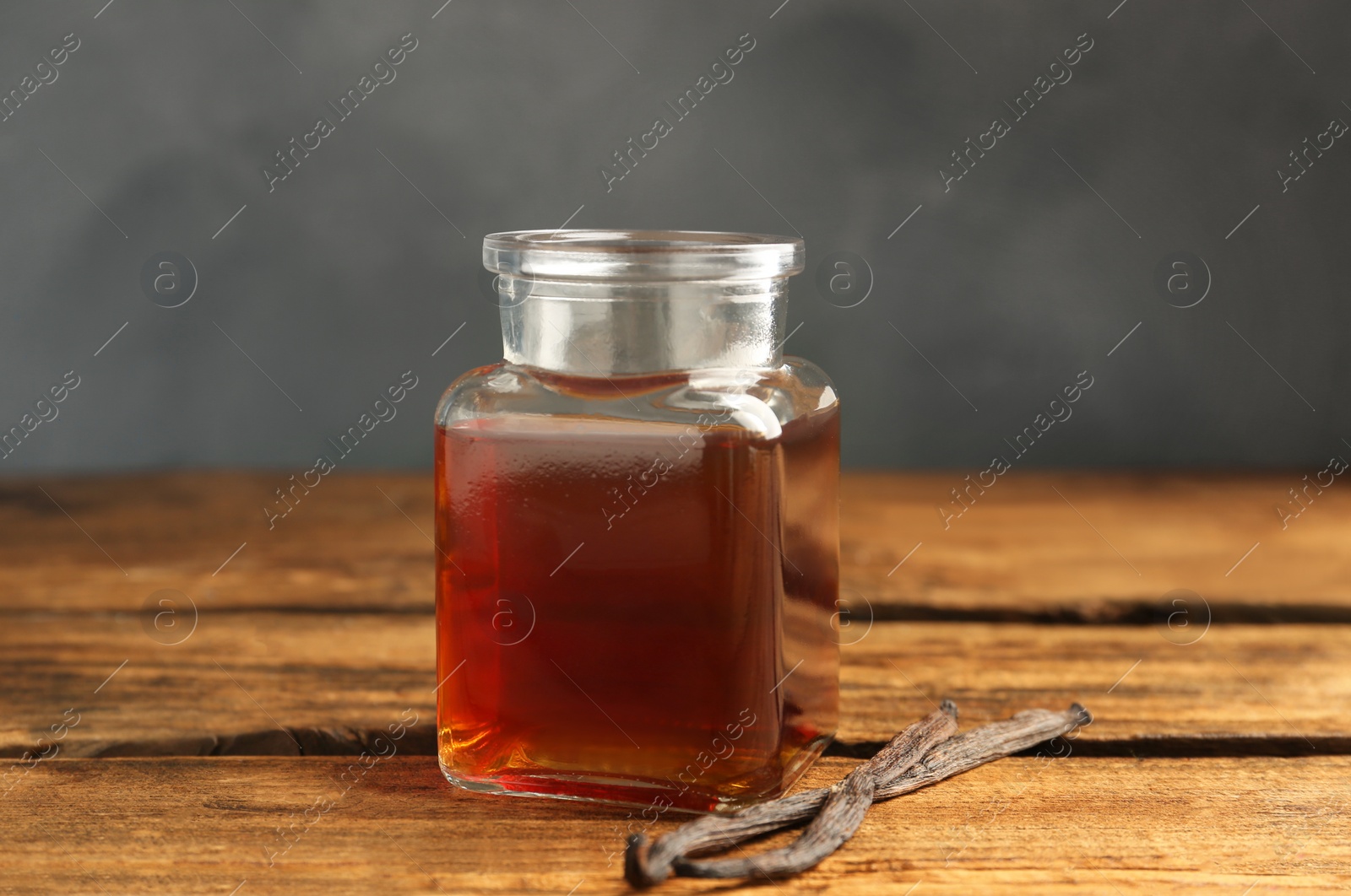 Photo of Aromatic homemade vanilla extract on wooden table