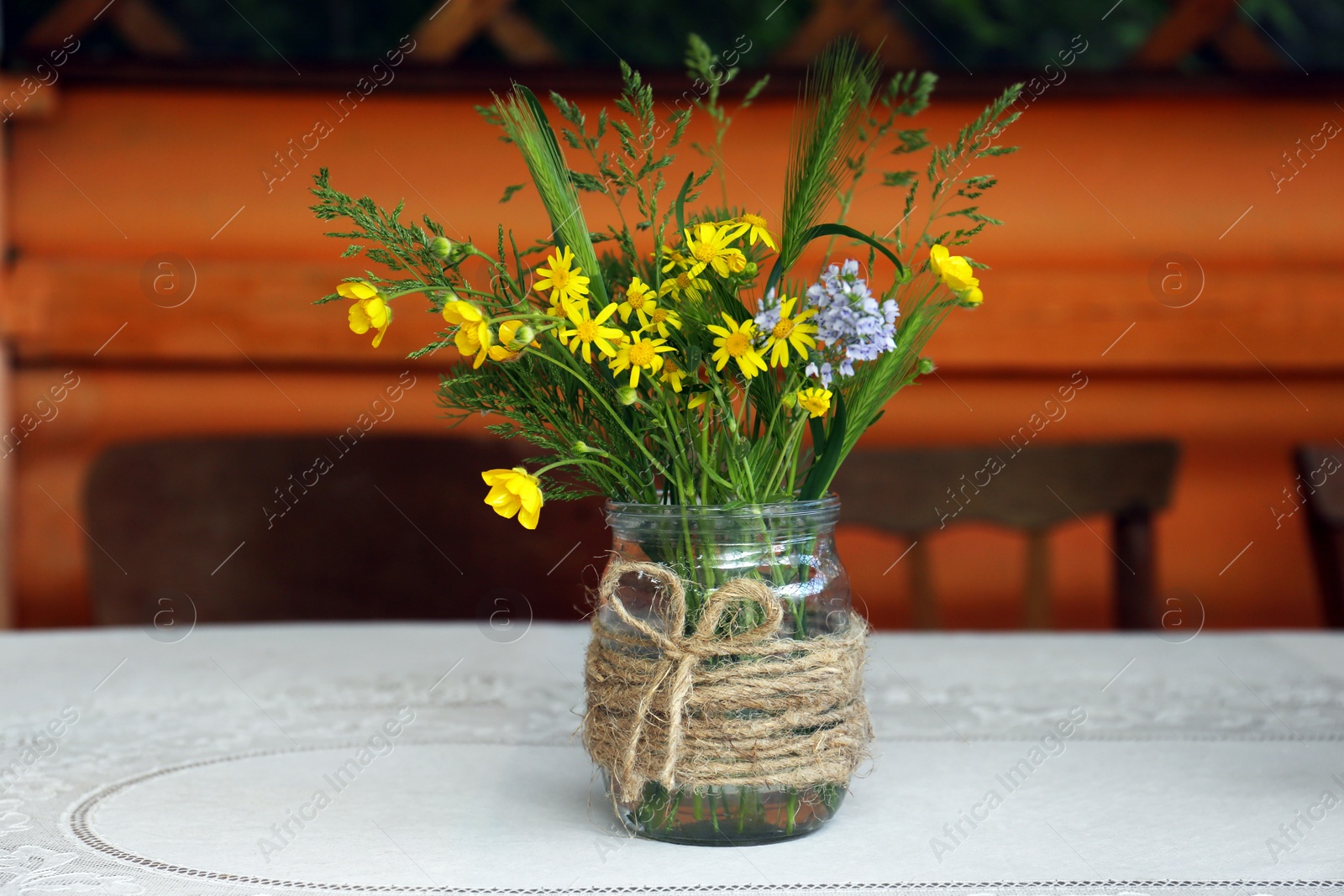 Photo of Bouquet of beautiful wildflowers in glass vase on table indoors