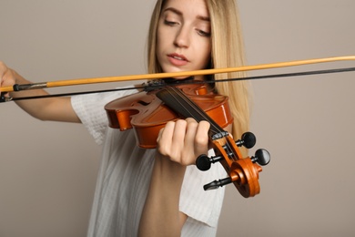 Photo of Beautiful woman playing violin on beige background, closeup