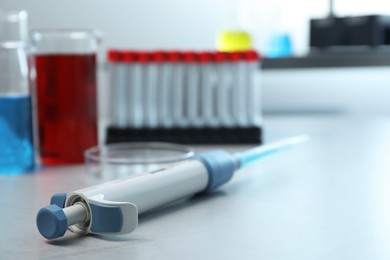 Laboratory analysis. Micropipette, beakers with liquids, petri dish and test tubes on grey table, closeup. Space for text