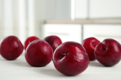 Delicious ripe plums on white wooden table, closeup. Space for text