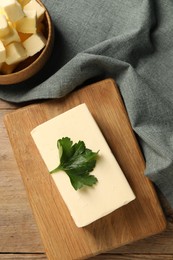 Tasty butter with parsley on wooden table, flat lay