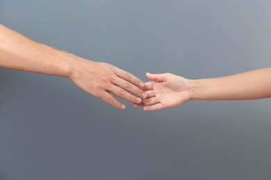 Photo of Man and woman giving each other hands on gray background. Concept of support and help