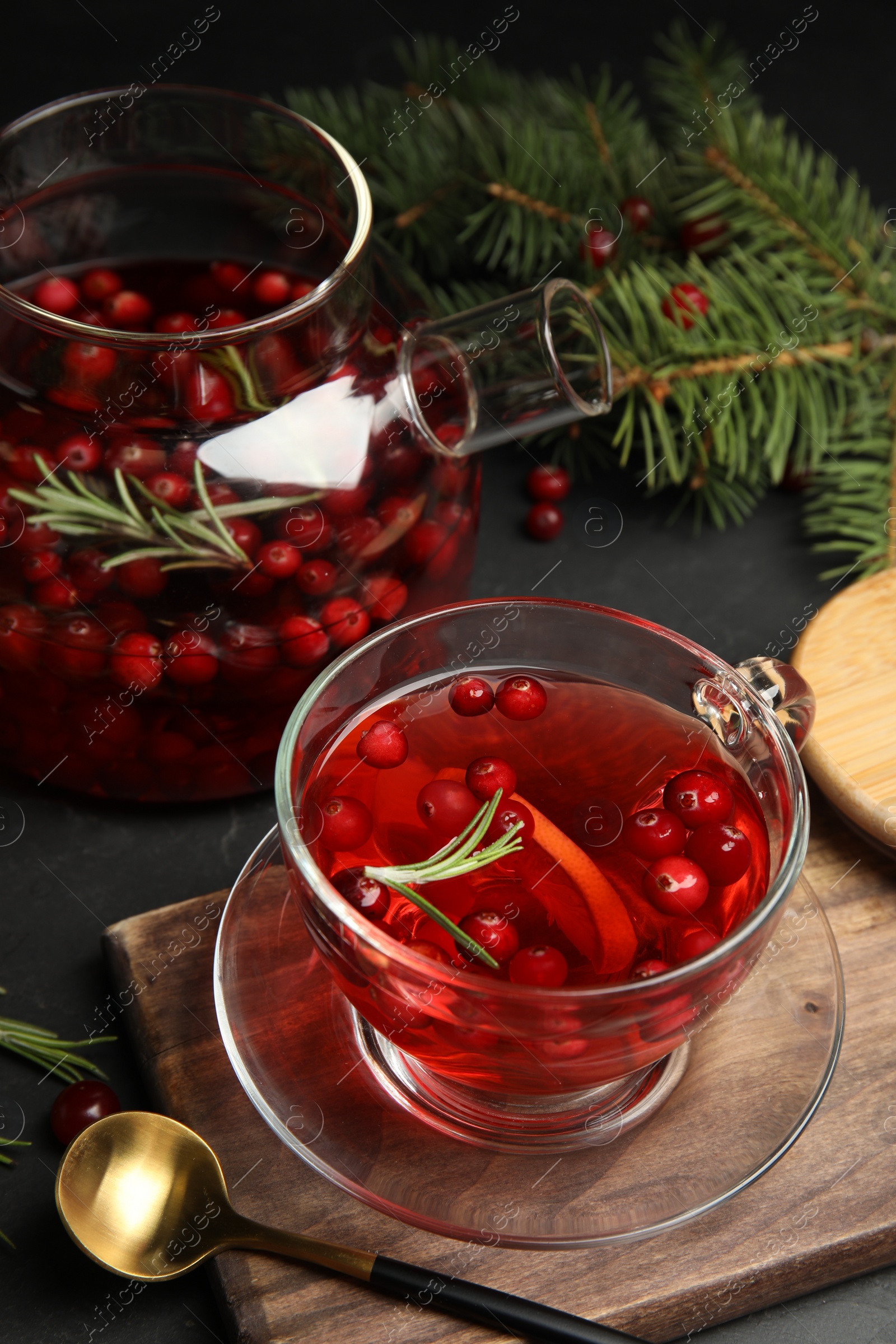 Photo of Tasty hot cranberry tea with rosemary and lemon on black table