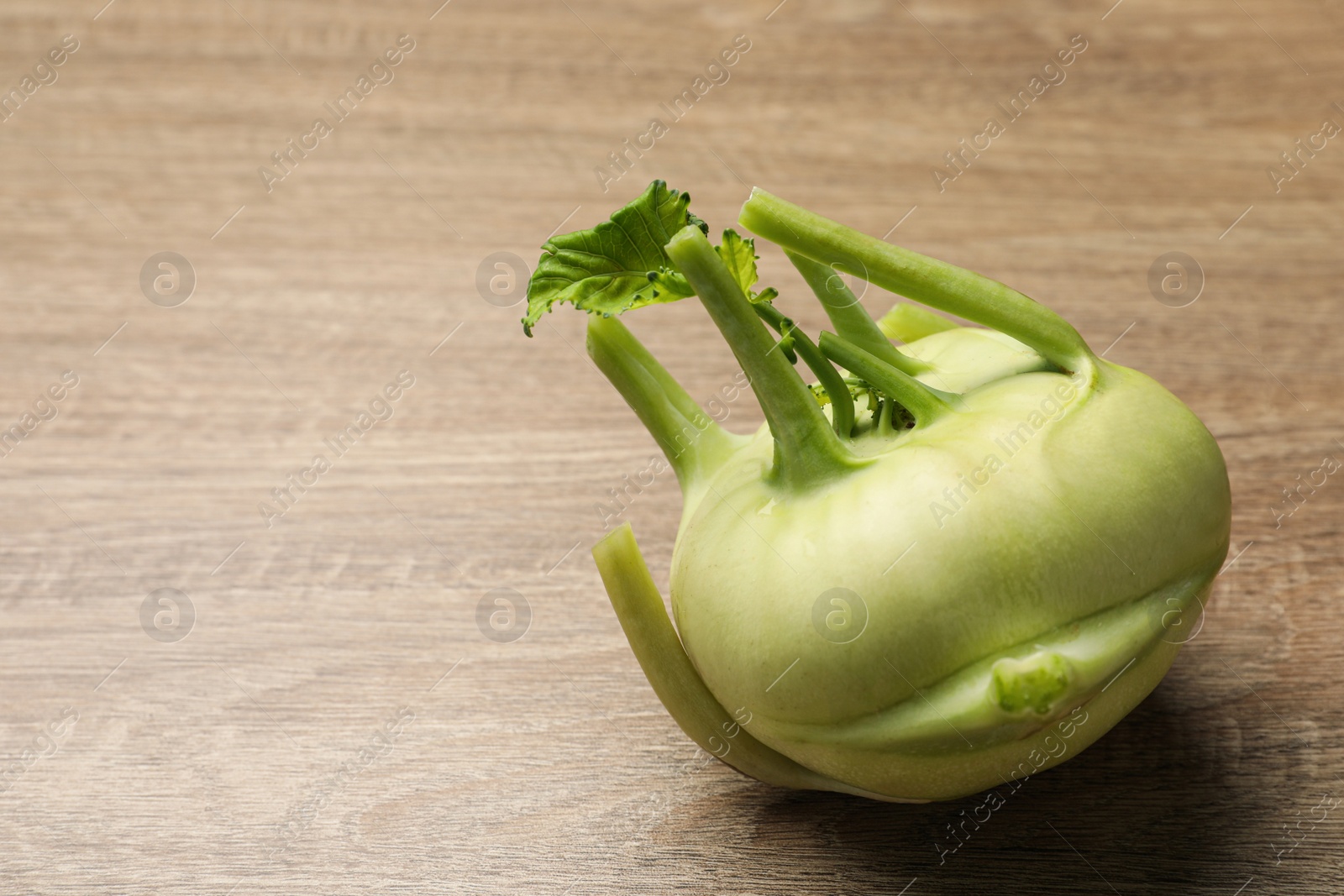 Photo of Whole ripe kohlrabi plant on wooden table. Space for text