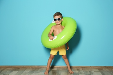 Photo of Cute little boy with inflatable ring near color wall