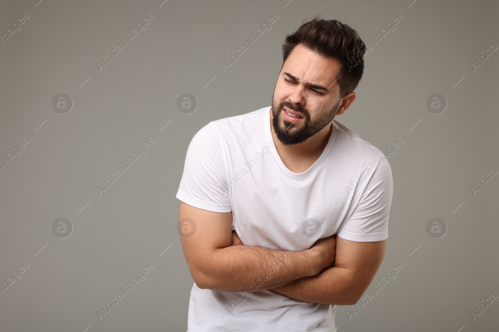 Photo of Young man suffering from stomach pain on light grey background