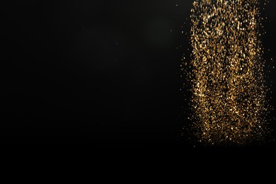 Shiny golden glitter falling down on black background, space for text. Bokeh effect