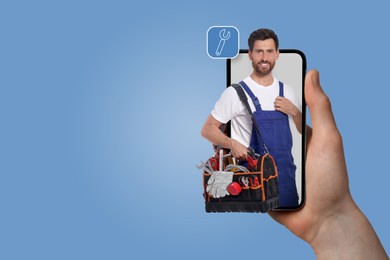 Image of Find plumber. Man using mobile phone on light blue background, closeup. Specialist looking out of gadget