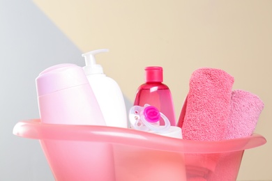 Photo of Baby cosmetic products and towels against color background, closeup