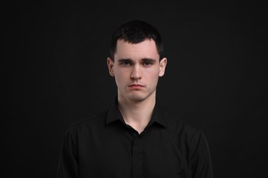 Photo of Portrait of sad man on black background