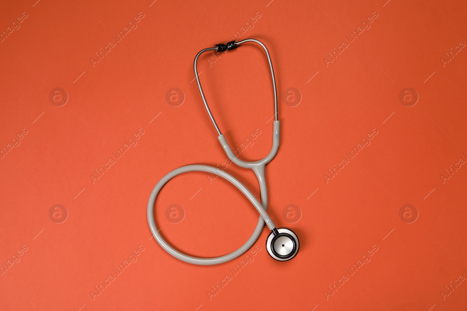 Photo of One stethoscope on crimson background, top view. Medical tool