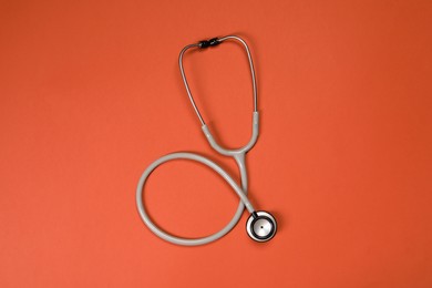 Photo of One stethoscope on crimson background, top view. Medical tool