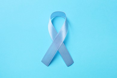 International Psoriasis Day. Ribbon as symbol of support on light blue background, top view