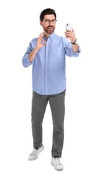 Smiling man taking selfie with smartphone and showing OK gesture on white background