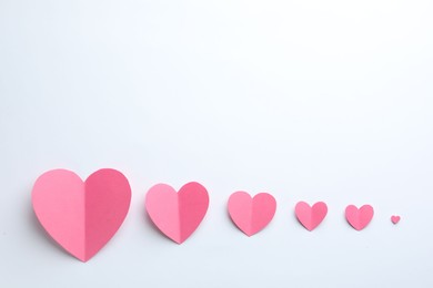 Pink paper hearts on white background, flat lay. Space for text