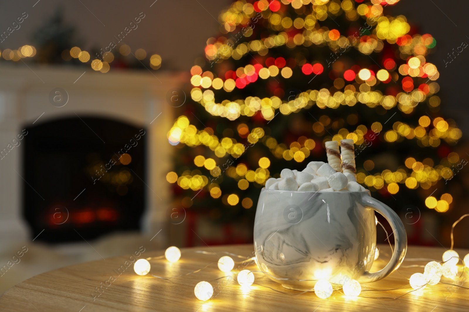 Photo of Christmas cocoa with marshmallows and wafer sticks in cup on wooden table indoors. Space for text